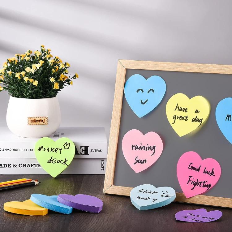 Heart-shaped sticky notes on a board, with blue, pink, yellow, and purple notes