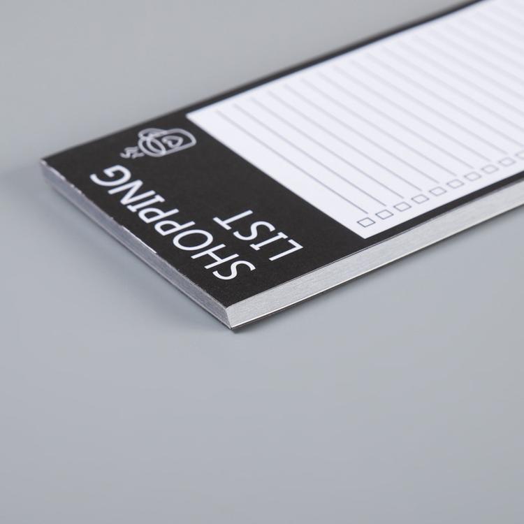 Shopping list pad close-up of black cover edge with lined sheet beneath