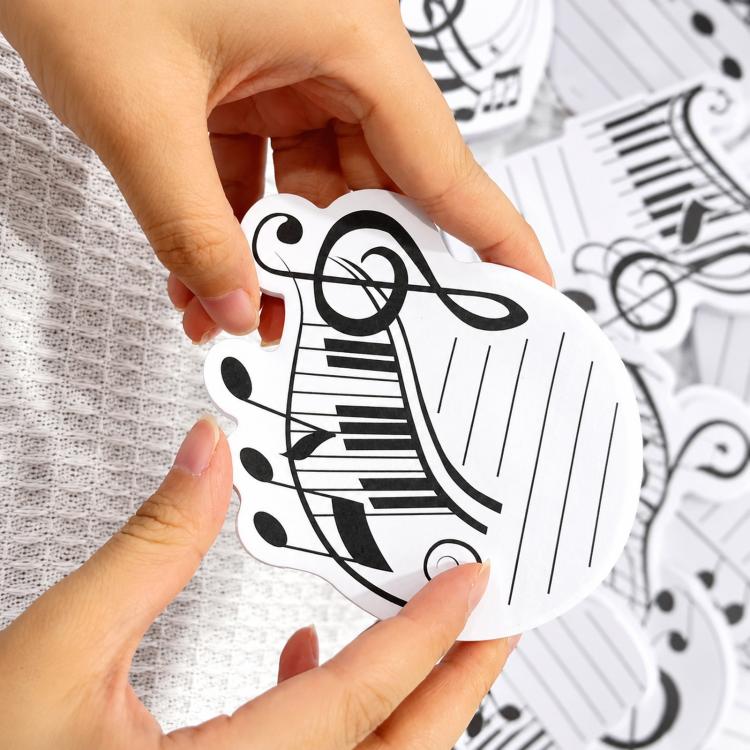 Hand placing a music staff sticky note with treble clef symbol onto paper surface