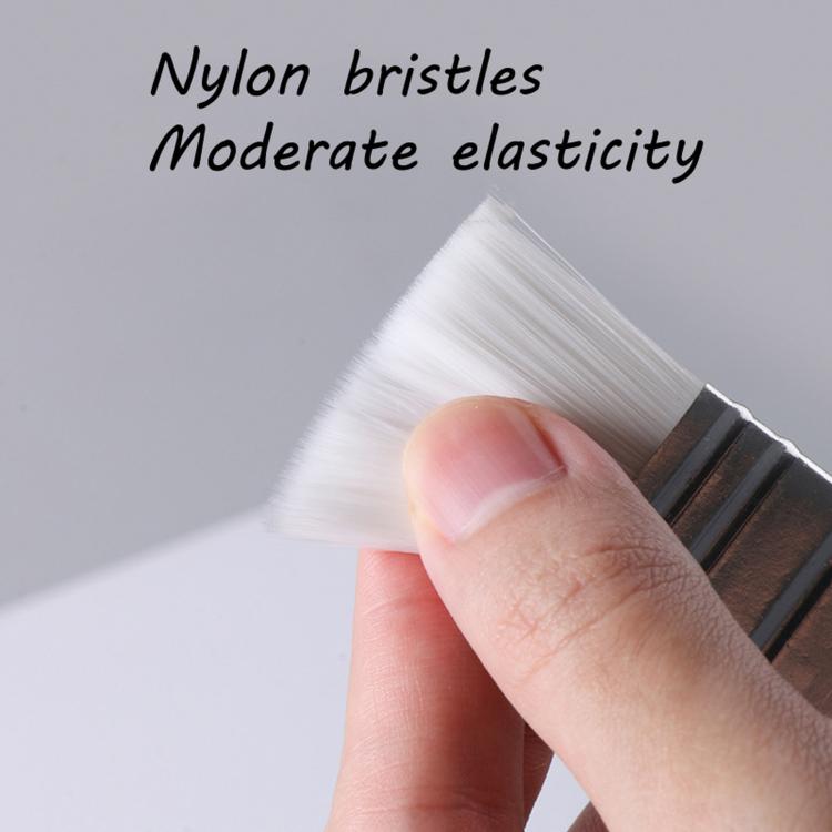 Nylon bristle paintbrush with silver ferrule and wooden handle held in hand