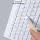 Paintbrush with wooden handle cleaning a white keyboard surface