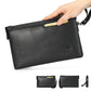 Black leather wristlet clutch bag with front emblem, wrist strap, and zip closure.