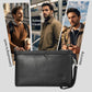 Black leather wristlet clutch bag with front emblem, zip closure, and wrist strap.