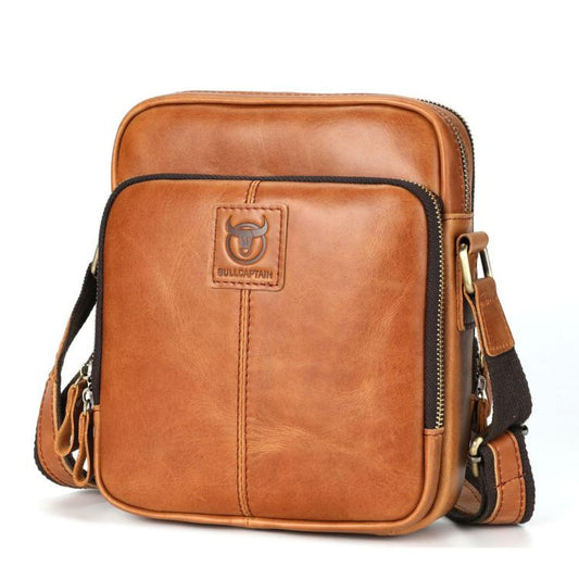 Men's tan leather crossbody bag with zip top and front logo patch.