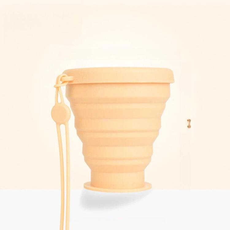 Apricot foldable silicone travel cup with lid and lanyard, shown from the side