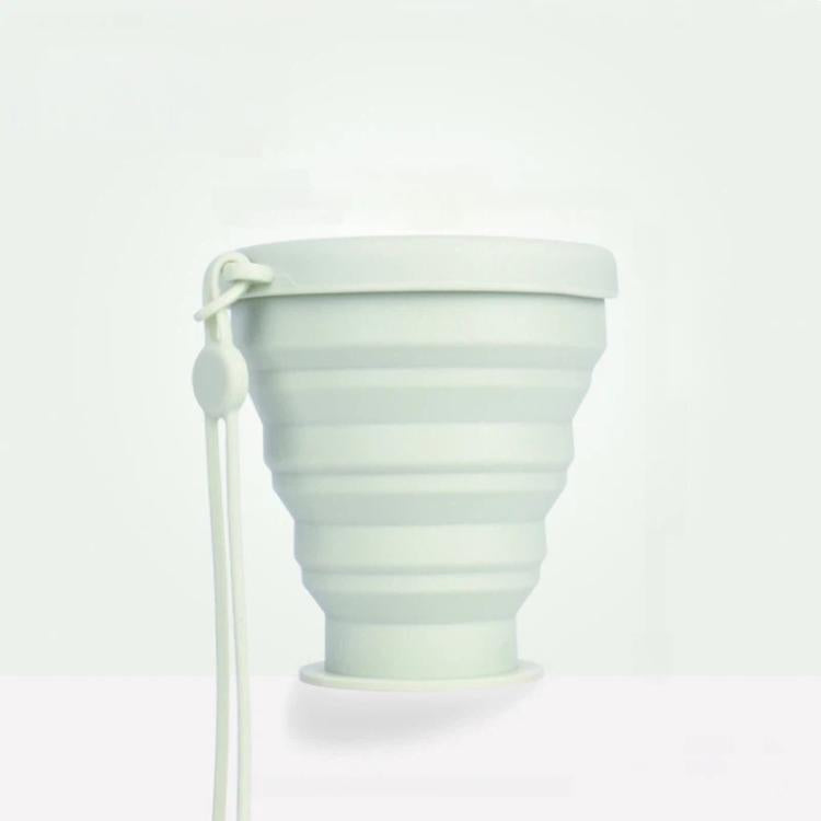 Light green collapsible silicone travel cup with lid and attached lanyard
