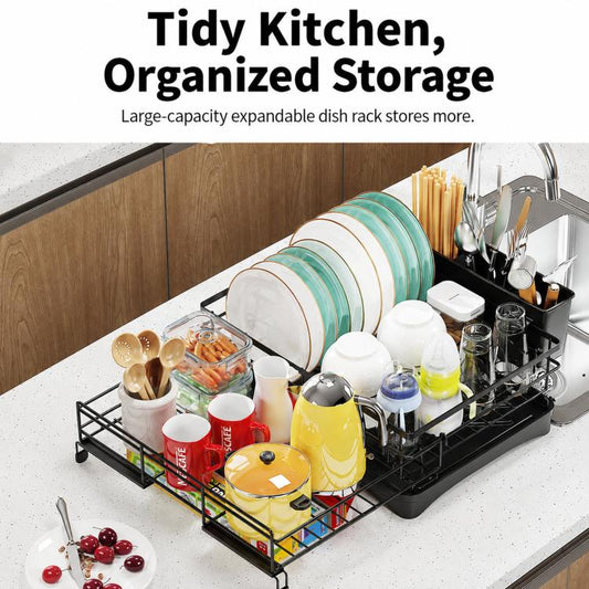 Black expandable dish drying rack with utensil holder and stacked plates on counter