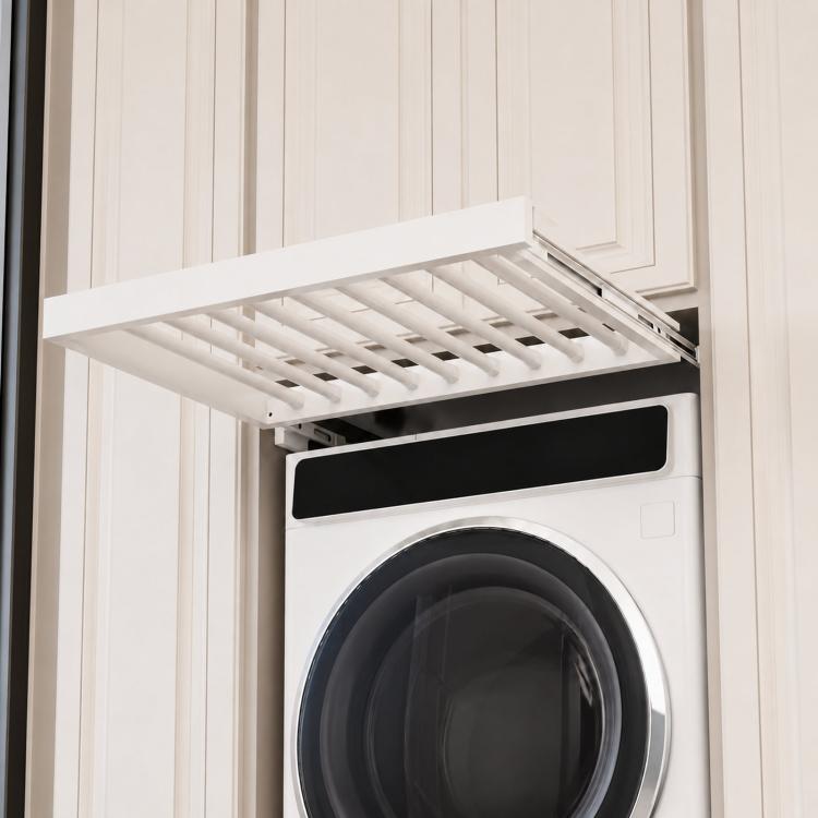 White pull-out laundry drying rack with slatted rods, extended over a front-loading washer