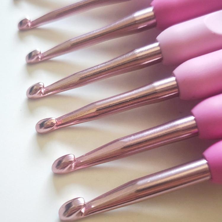 Row of aluminum crochet hooks with pink soft handles, close-up of metal tips