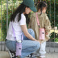 Purple mesh bottle holder bag with adjustable strap and front pocket, worn crossbody