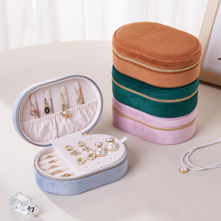 Stacked velvet oval jewelry cases in light blue, green, pink and brown with zippers