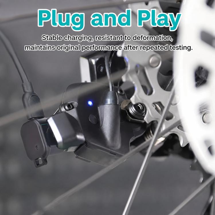 Black charging adapter plugged near bike components with visible indicator light