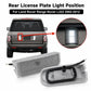 Rear license plate light assembly with clear lens, shown near vehicle mounting area