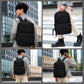 Black laptop backpack worn by a man, featuring side handle and front zip pocket