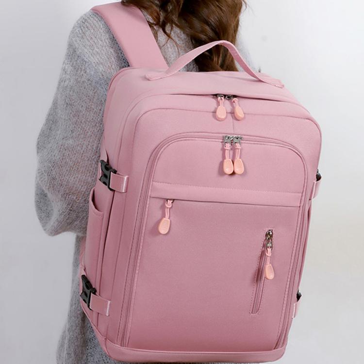 Pink travel backpack worn on shoulder with front zip compartments and top handle