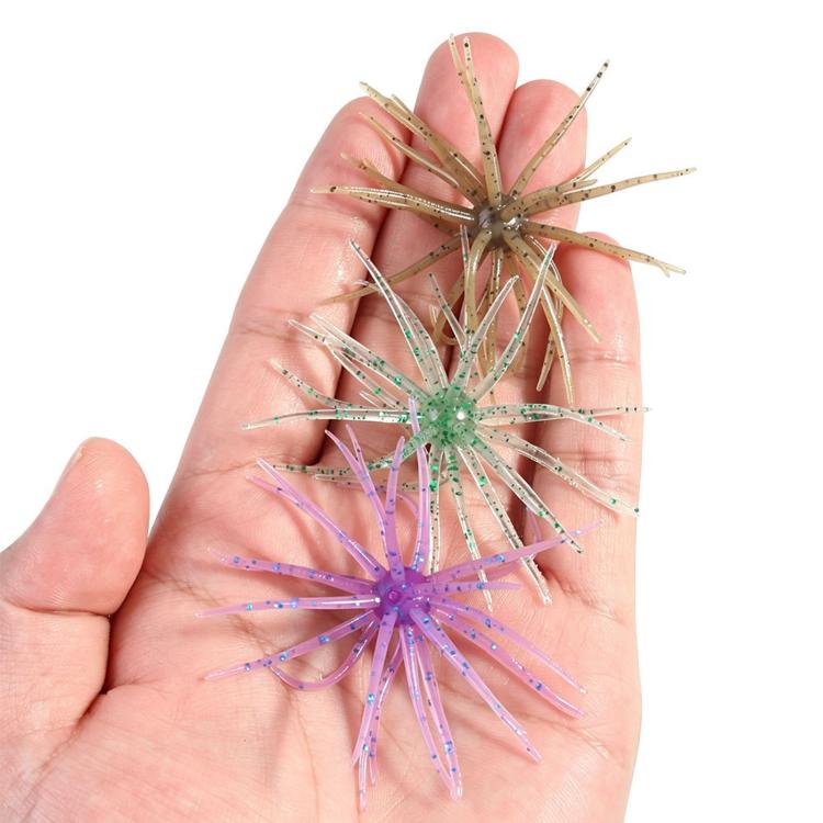 Sea urchin soft fishing lures held in hand, purple and green tentacles