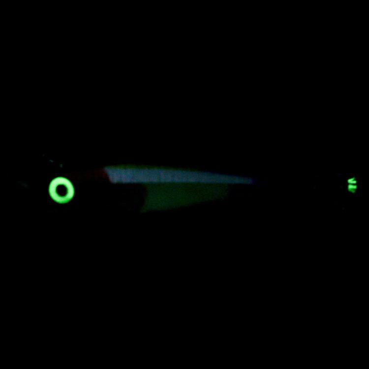 Glow squid jig lure shown in dark, bright green illuminated eye and stripes