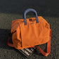 Expandable travel duffel bag in orange with blue top handles and two side straps