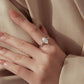 Teardrop moissanite ring on hand with sterling silver band and side accent stones