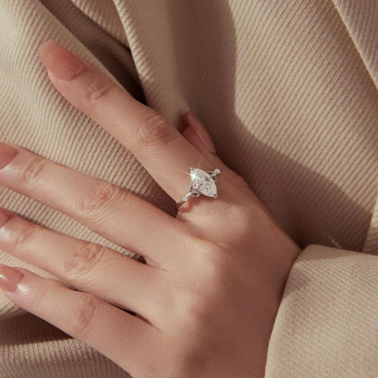 Teardrop moissanite ring on hand with sterling silver band and side accent stones