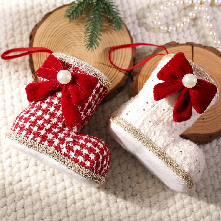 Close-up of two hanging boot ornaments: red plaid and white, each with red bow and pearl.