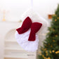 White sequin-look hanging stocking ornament with red bow and ribbon tails