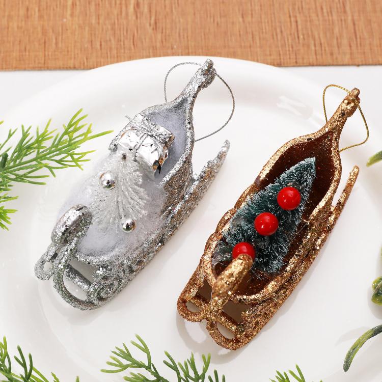 Pair of glitter sleigh ornaments: silver and gold, with pine-tree and red berry details