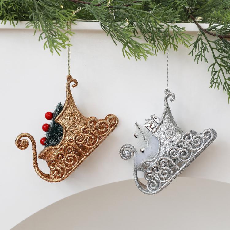 Hanging pair of glitter sleigh ornaments in gold and silver with pine-tree accents