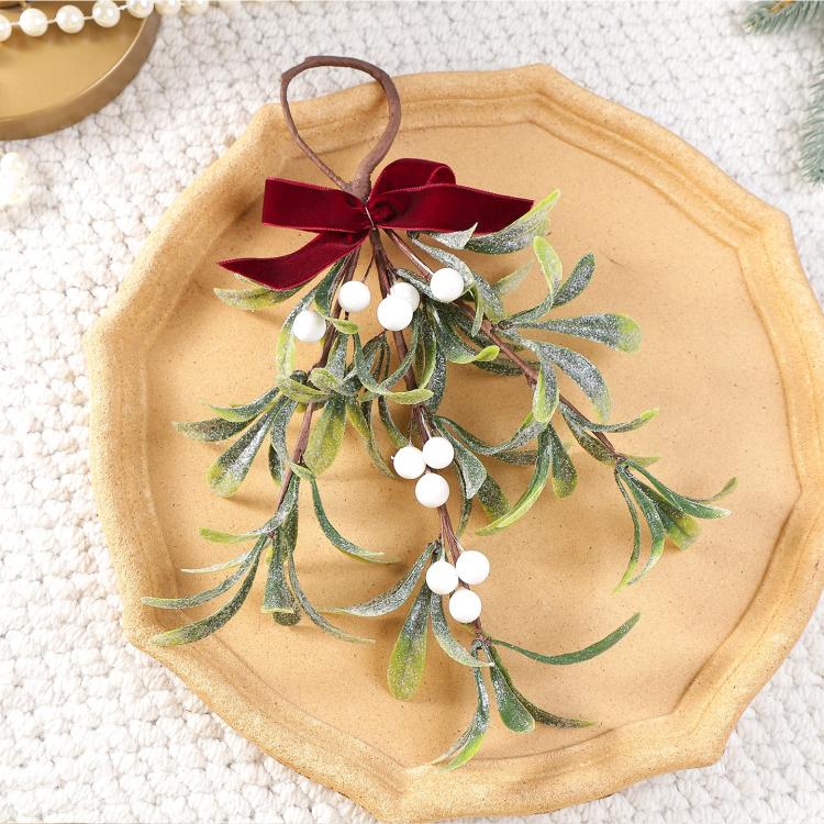 Artificial mistletoe ornament with red velvet bow and white bead berries on frosted greenery
