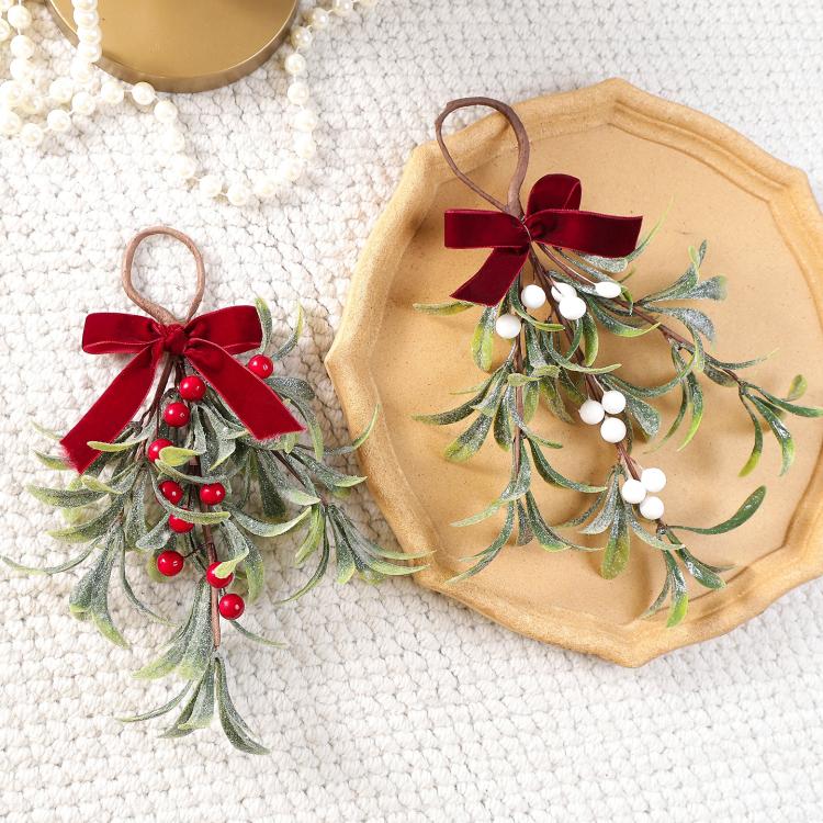 Artificial mistletoe hanging ornaments on a tray: one red-berry, one white-berry, red velvet bows