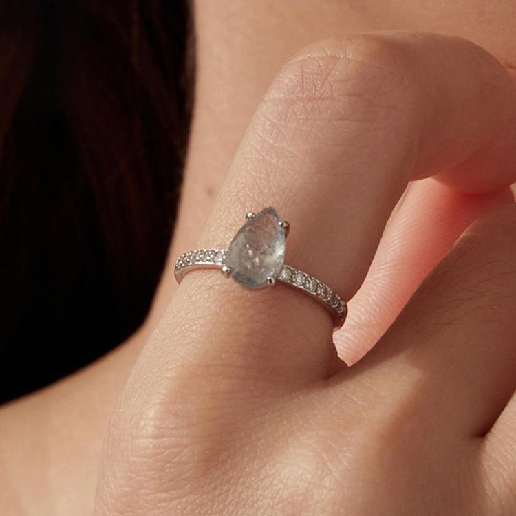 Sterling silver ring with teardrop center stone and pavé band on a finger