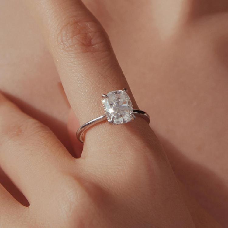 Sterling silver moissanite ring on finger with square center stone and four-prong top