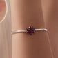 Silver bangle bracelet featuring a magenta devil flower charm with pink gemstone center