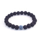 Matte black lava bead bracelet with single light blue crackle bead