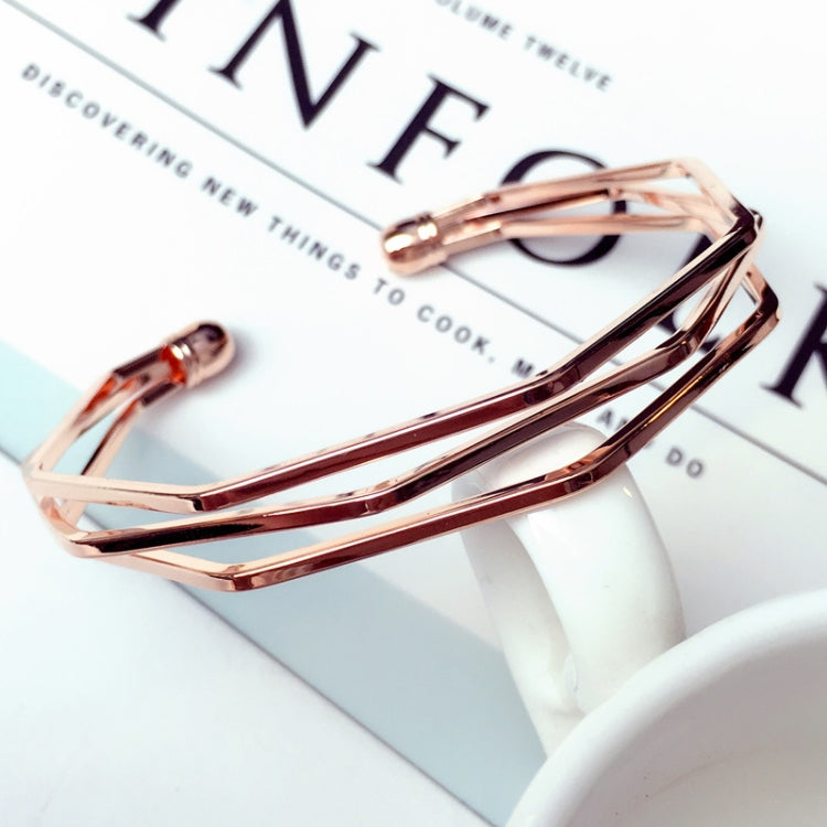 Rose gold multi-layer open cuff charm bracelet on a white tabletop display.