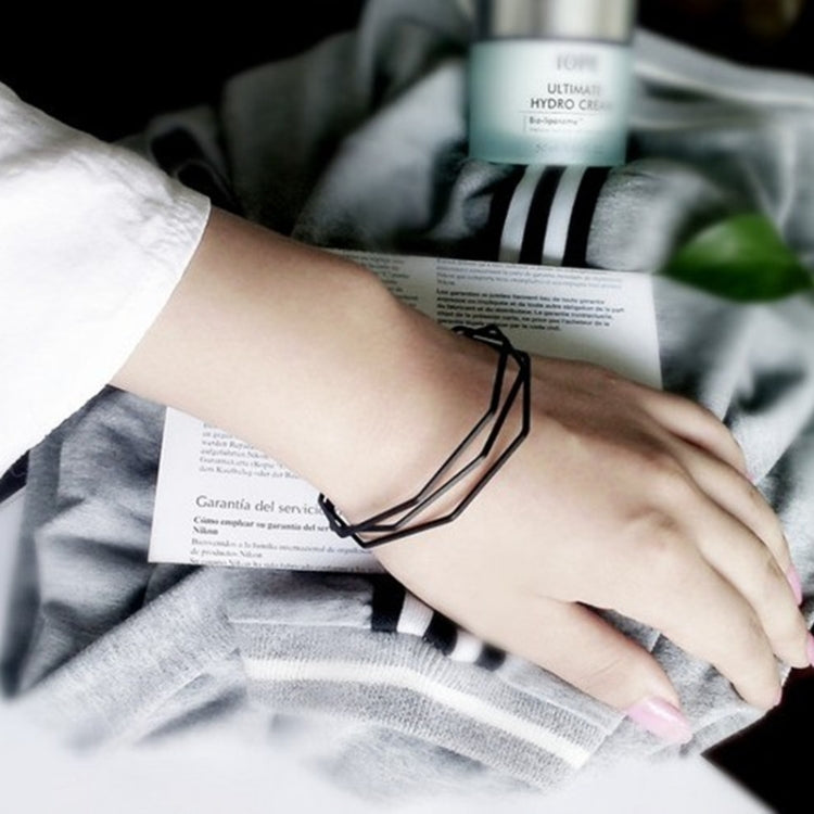 Black multi-layer open cuff charm bracelet worn on wrist with angular links.