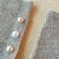 Pearl stud collar pins on gray and tan knit fabric, three beads visible