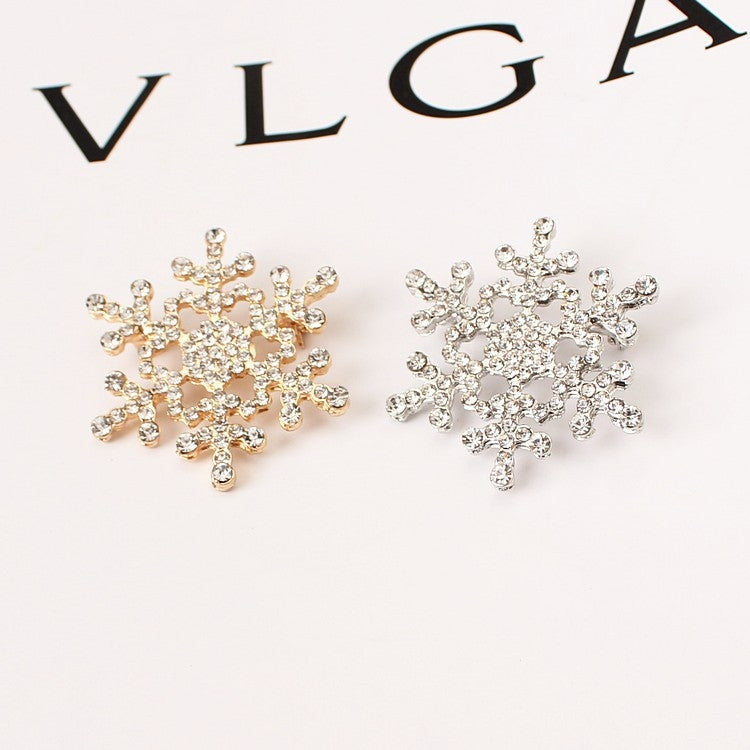 Gold- and silver-tone rhinestone snowflake brooches, two designs side by side