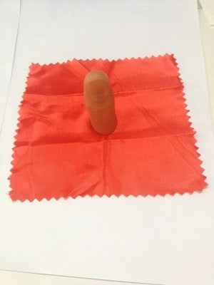 Rubber thumb tip on red cloth square, shown on tabletop