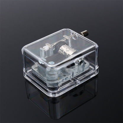 Clear acrylic DIY music box with exposed mechanism and crank handle, front view