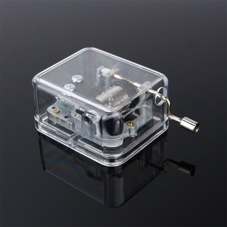 Clear acrylic DIY music box with winding handle and exposed mechanism, side view