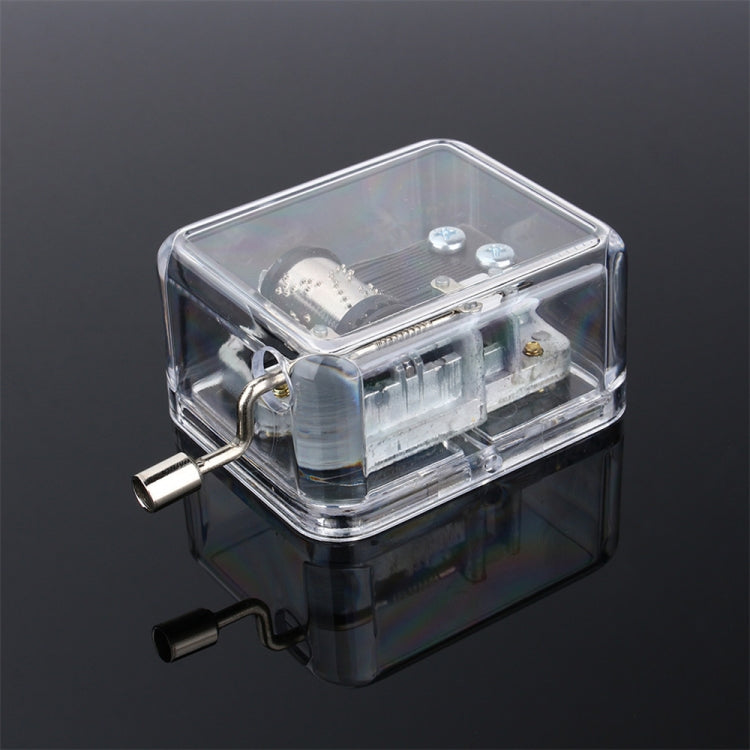 Clear acrylic DIY music box showing front-side gearing and crank handle, 3/4 view