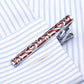 Red enamel tie clip with white scroll pattern and shiny silver clasp