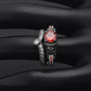 Skull ring with red round center gemstone, black band, and small clear stone detailing