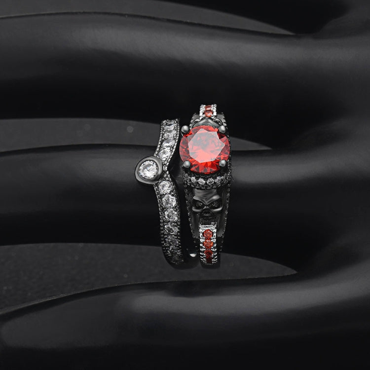 Skull ring with red round center gemstone, black band, and small clear stone detailing