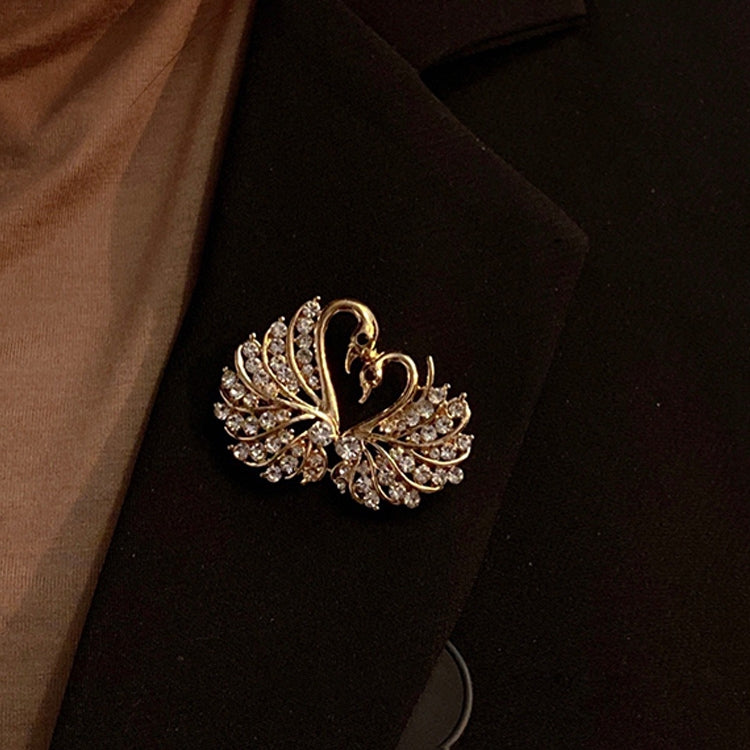 Crystal swan brooch pinned on a dark lapel with gold-tone rhinestones
