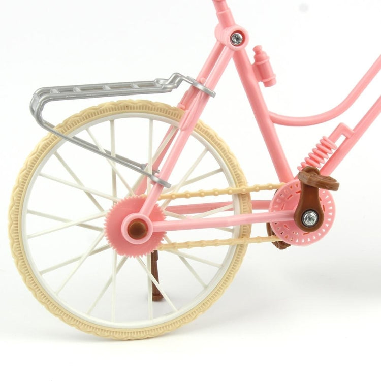 Close-up mini dollhouse bicycle: pink fork, tan wheel rims, gray front guard