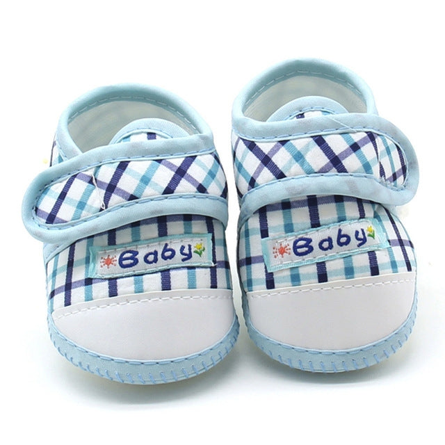 Baby prewalker shoes with light blue plaid fabric and “Baby” label on front