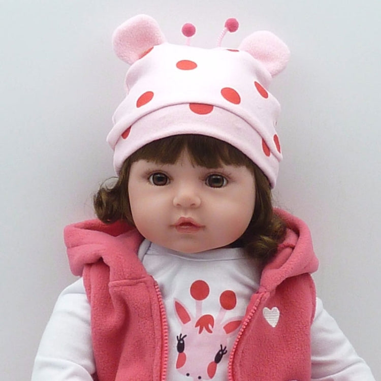 Baby girl silicone doll close-up wearing a pink animal-ear hat and pink hooded outfit