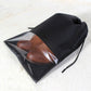 Black waterproof shoe pouch with transparent panel and drawstring, holding brown shoes